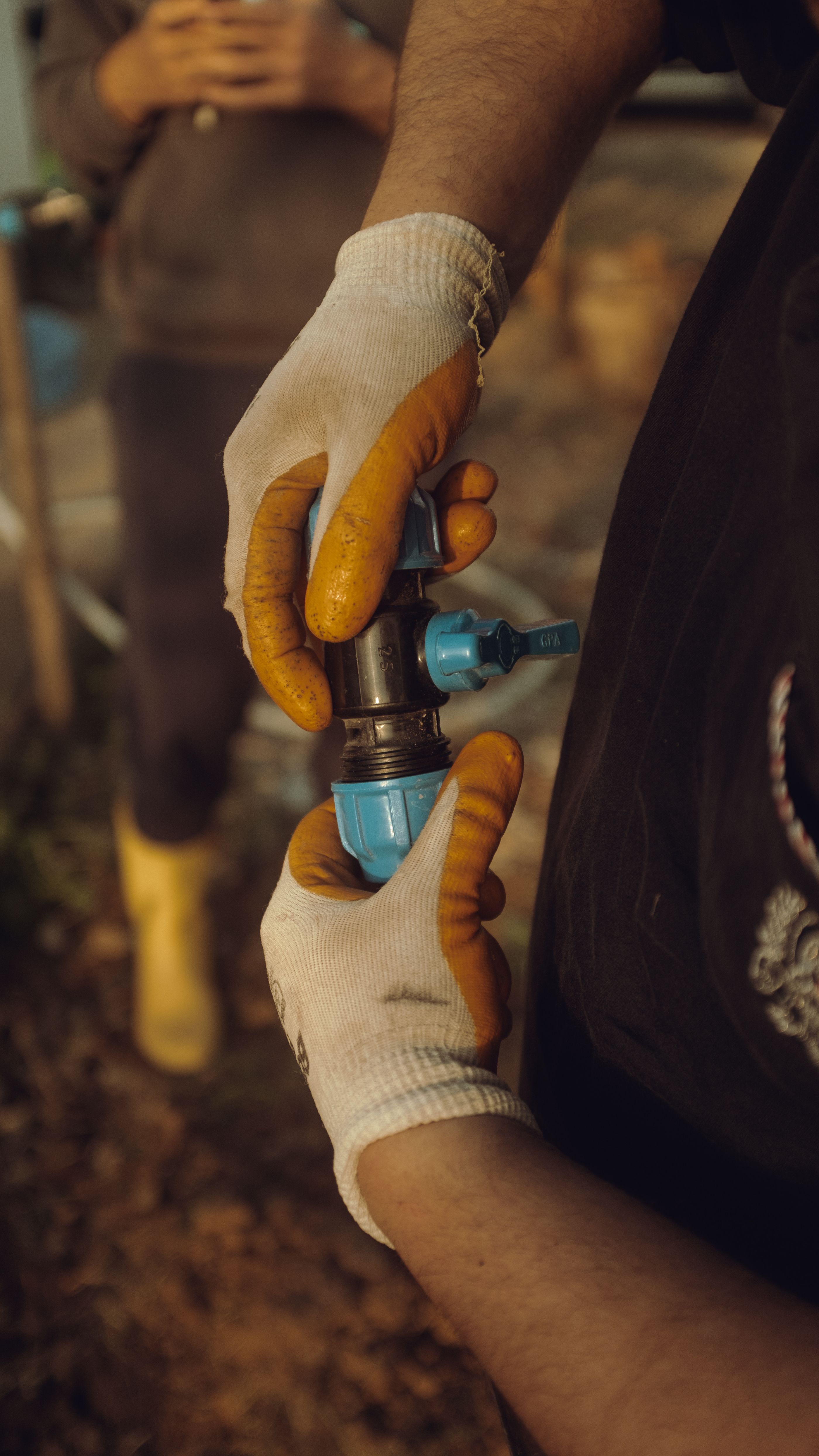 Technician's gloved hands assembling outdoor water piping